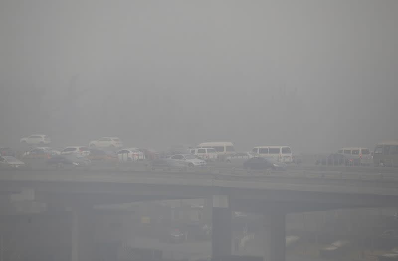 FILE PHOTO: Vehicles drive amid heavy smog in Beijing