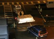 Police officers escort an airport vehicle transporting what is believed to be debris from a Boeing 777 plane that washed up on Reunion Island, at Roland Garros airport on July 31, 2015