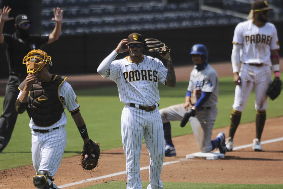 San Diego Padres third baseman Manny Machado signals to the dugout to review a call during the third inning of the team's baseball game against the Los Angeles Dodgers on Wednesday, Sept. 16, 2020, in San Diego. Dodgers' Mookie Betts was called safe on the play at home but after review the call was overturned. (AP Photo/Derrick Tuskan)