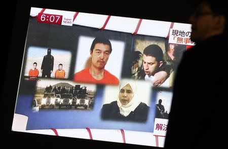 A man walks past a TV screen broadcasting a news program about Islamic State hostages Jordanian air force pilot Muath al-Kasaesbeh (top R) and Japanese journalist Kenji Goto (top C), along a street in Tokyo January 29, 2015. REUTERS/Yuya Shino