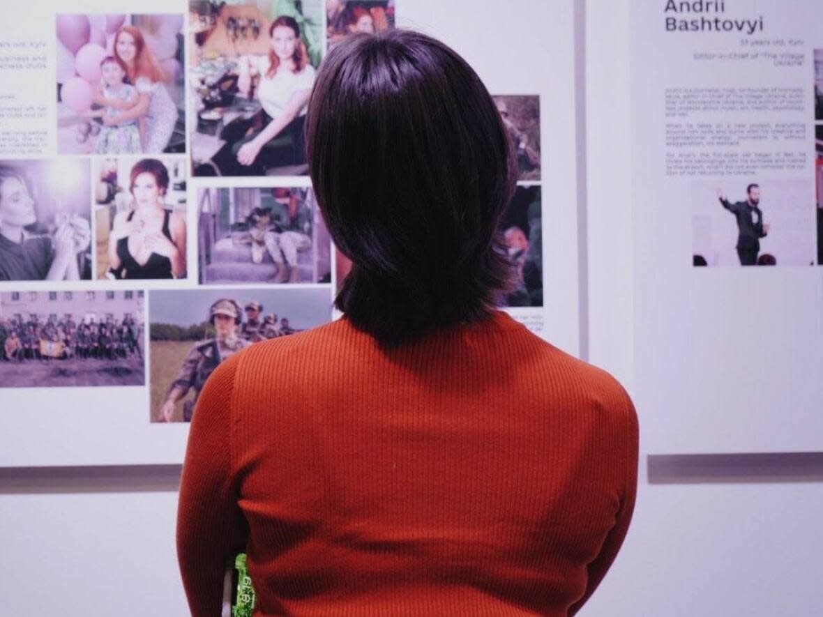 An onlooker takes in the pop-up photo exhibition at the SAW gallery in Ottawa ahead of the one-year anniversary of the Russian invasion of Ukraine. (Anastasiia Turetska - image credit)