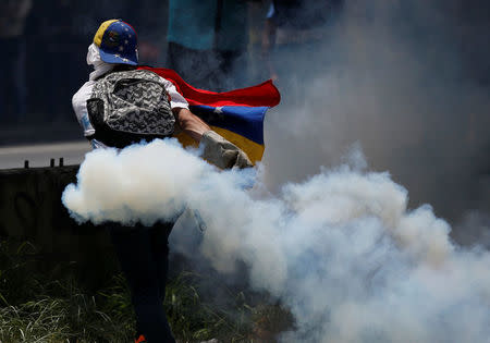 A demonstrator carries a tear gas canister during clashes with security forces during an opposition rally in Caracas, Venezuela April 6, 2017. REUTERS/Carlos Garcia Rawlins