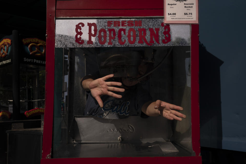 Sandy Martinez, 32, prepares a popcorn machine ahead of reopening at Adventure City amusement park in Anaheim, Calif., Thursday, April 15, 2021. The family-run amusement park that had been shut since March 2020 because of the coronavirus pandemic reopened on April 16. Martinez is among the former employees who came back to work. "I didn't look for any other job because I love working here," said Martinez, who began her career at the park when she was 18. "They are like family to me." (AP Photo/Jae C. Hong)