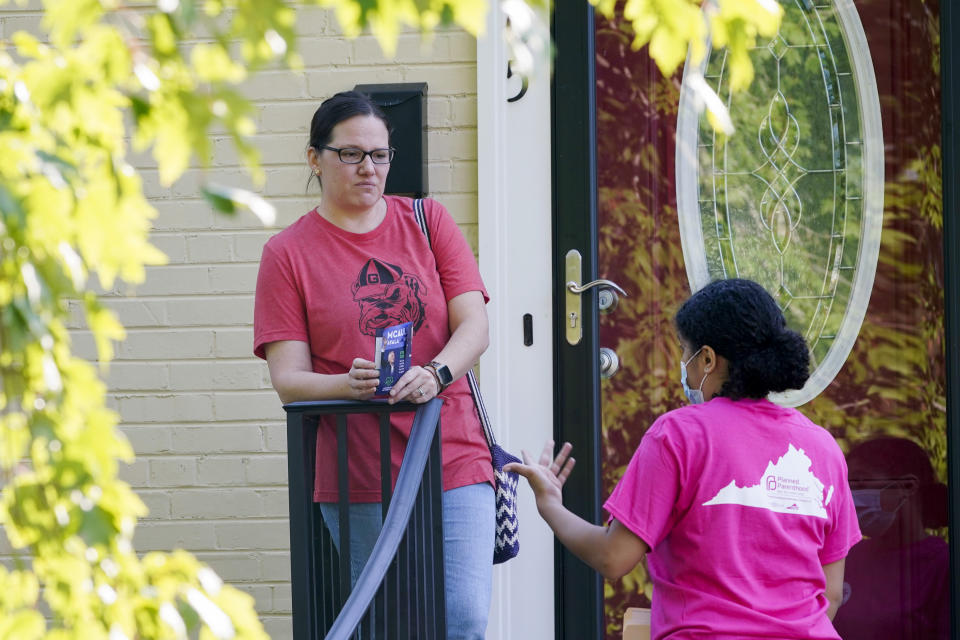 In this Saturday, Oct. 16, 2021, photo Han Jones of Planned Parenthood Advocates of Virginia , right, talks with Democratic voter, Danielle Clark while canvassing the area to encourage voters to vote in Richmond, Va. (AP Photo/Steve Helber)