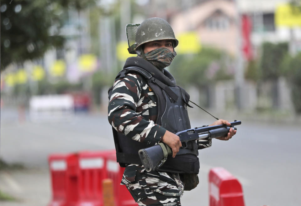 A security person stands guard at a deserted street during a security lockdown in Srinagar, Indian controlled Kashmir, Monday, Aug. 12, 2019. Troops in India-administered Kashmir allowed some Muslims to walk to local mosques alone or in pairs to pray for the Eid al-Adha festival on Monday during an unprecedented security lockdown that still forced most people in the disputed region to stay indoors on the Islamic holy day. (AP Photo/Mukhtar Khan)