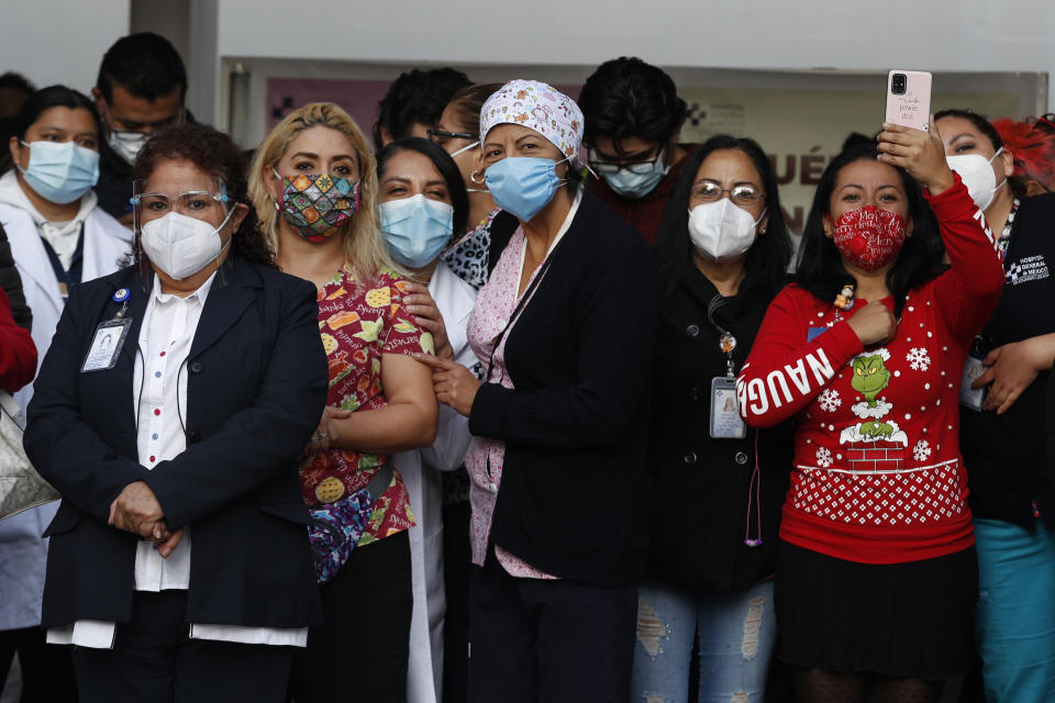 Hospital workers watch fellow health workers get injected with the COVID-19 vaccinations at the General Hospital in Mexico City, early Thursday, Dec. 24, 2020. The first batches of vaccines produced by Pfizer and its German partner, BioNTech arrived the previous day. (AP Photo/Eduardo Verdugo)