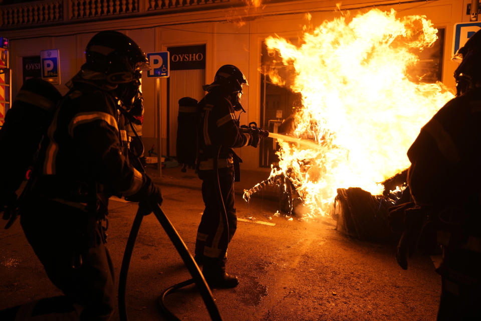 Firefighters extinguish a garbage container burned by demonstrators after a protest against the amnesty at the headquarters of Socialist party in Madrid, Spain, Thursday, Nov. 16, 2023. Spain's acting Socialist prime minister, Pedro Sánchez, has been chosen by a majority of legislators to form a new leftist coalition government in a parliamentary vote. The vote came after nearly two days of debate among party leaders that centered almost entirely on a highly controversial amnesty deal for Catalonia's separatists that Sánchez agreed to in return for vital support to get elected prime minister again. (AP Photo/Manu Fernandez)