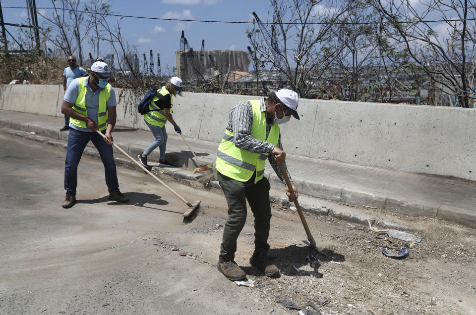 Volunteers who traveled from the Bekaa valley in Eastern Lebanon to help clean the city, damaged homes and give other assistance, clean a street near the site of last week's explosion, in Beirut, Lebanon, Tuesday, Aug. 11, 2020. The explosion that tore through Beirut left around a quarter of a million people with homes unfit to live in. In the absence of the state residents of Beirut opened their homes to relatives, friends and neighbors. And on the streets, it was young volunteers with brooms, not government workers, who swept the streets littered with shattered glass. (AP Photo/Hussein Malla)