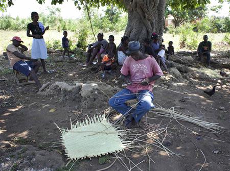 Sourel Brito, one of the families whose homes will be expropriated by Haiti's government to make way for an international airport, weaves a basket while sitting under a tree with neighbors on Ile-a-Vache island, off Haiti's south coast, March 25, 2014. REUTERS/stringer