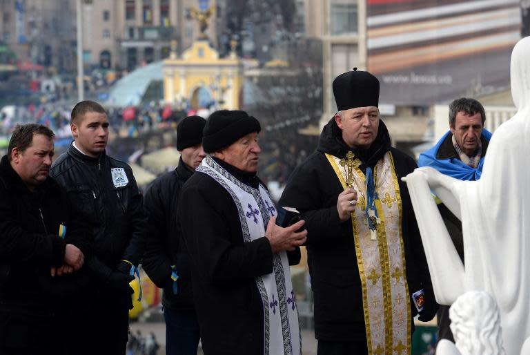 Priests and faithful of the Ukrainian Greek Catholic Church pray in front of a statue of the Mother of God at the Independence Square in Kiev on December 4, 2013