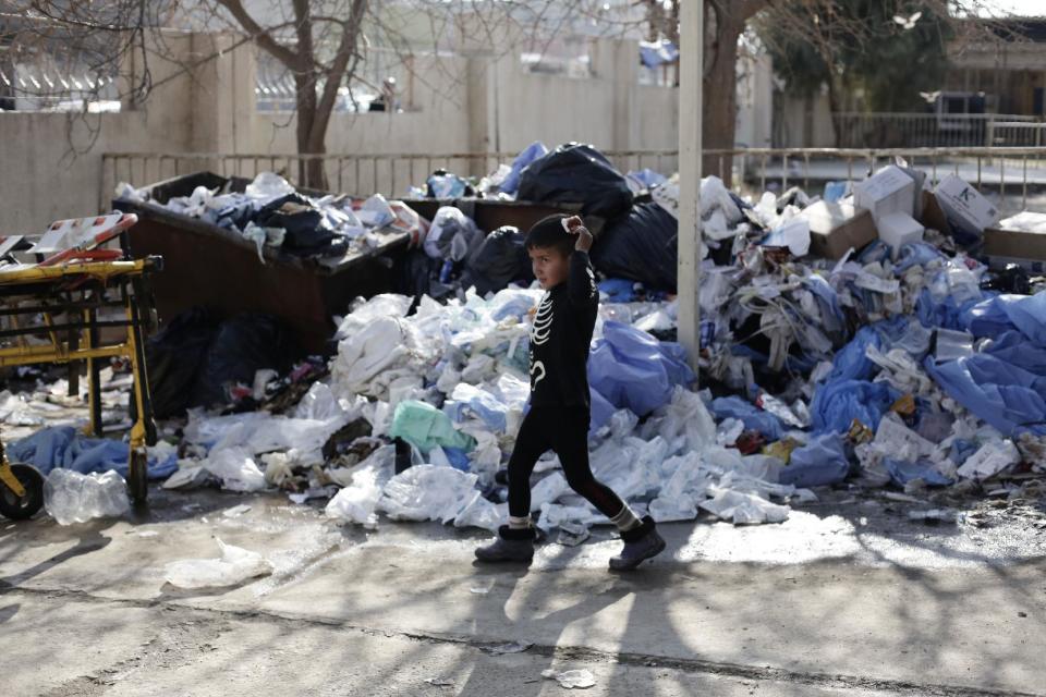 A child with a head wound walks past a large pile of medical waste at a hospital in the Zahra district of Mosul, Iraq, Tuesday, Feb. 14, 2017. The staff here, who treat people injured by the fight to oust Islamic State militants, say the Iraqi government is offering no help to remove the waste that is steadily piling up.(AP Photo/Maya Alleruzzo)