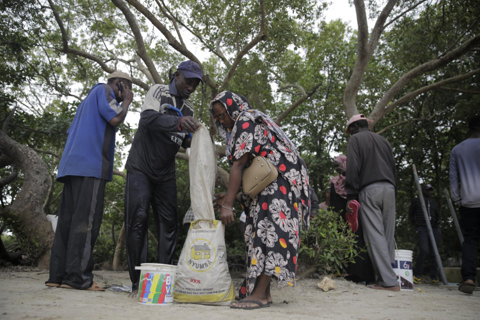 A woman loads fish to be sold at a local market near mangrove trees in Gazi Bay, Kenya on Sunday, June 12, 2022. (AP Photo/Brian Inganga)