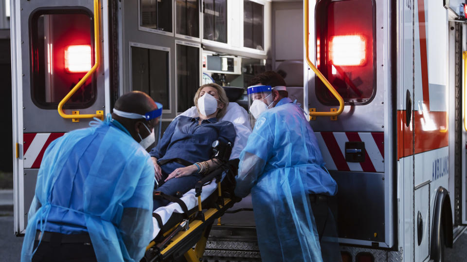 paramedics putting a person on a stretcher into the back of an ambulance