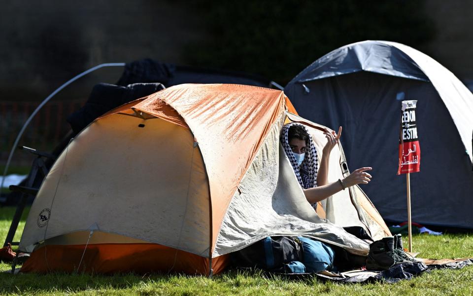 A protester looks out of a tent outside Oxford University Museum of Natural History