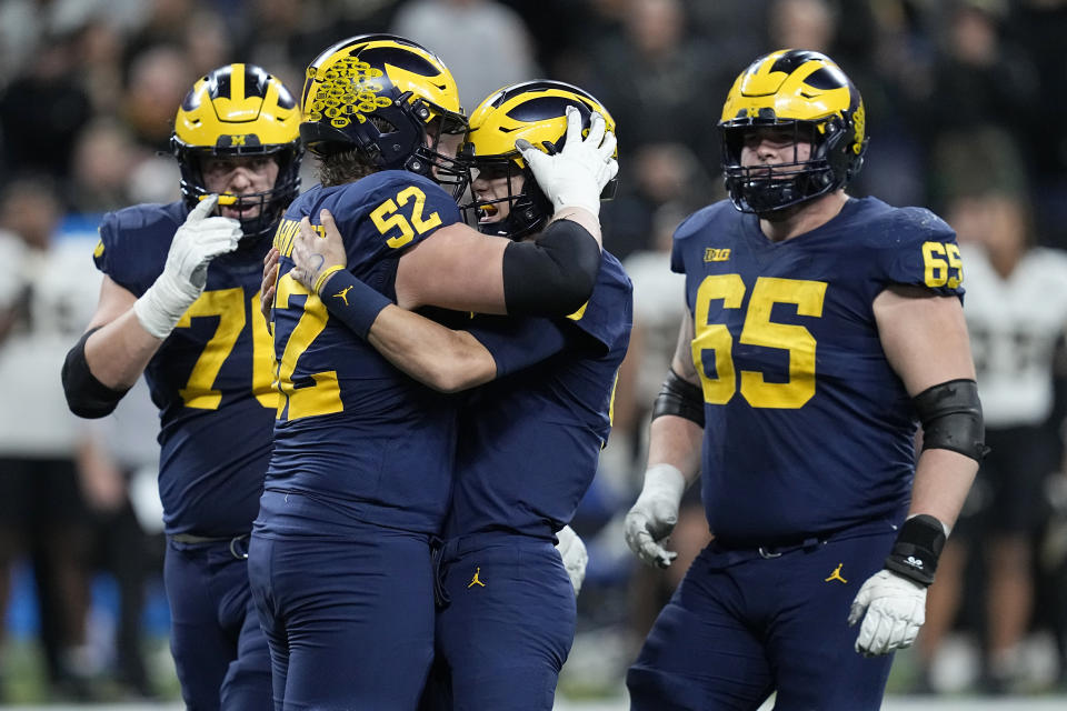 Michigan quarterback J.J. McCarthy is congratulated by teammates Kechaun Bennett (52), Ryan Hayes, left, and Zak Zinter (65) after throwing a touchdown pass during the second half of the Big Ten championship NCAA college football game against Purdue, Saturday, Dec. 3, 2022, in Indianapolis. (AP Photo/Darron Cummings)
