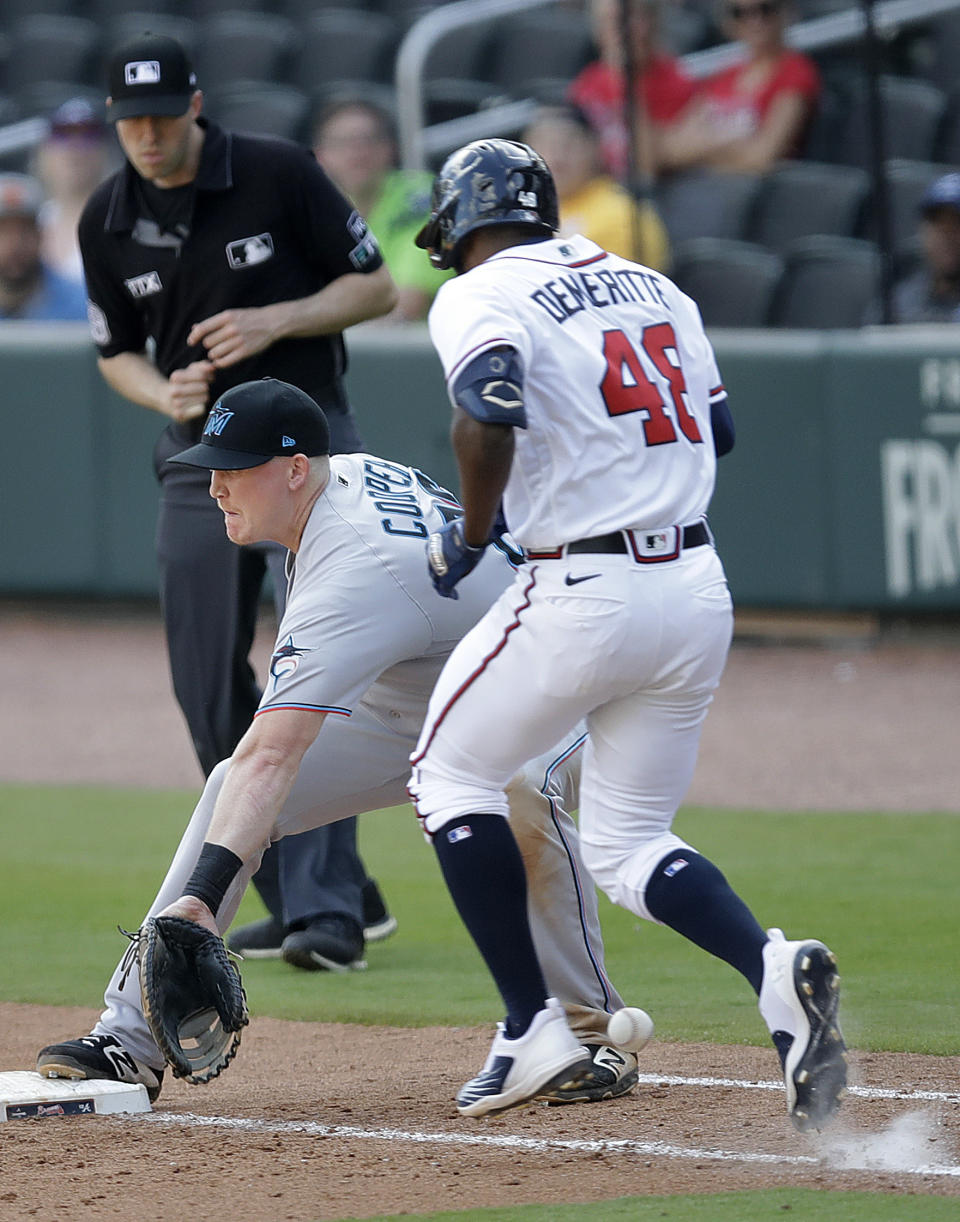 Miami Marlins' Garrett Cooper, front left, cannot make the catch at first base, allowing Atlanta Braves' Travis Demeritte (48) to reach base, in the ninth inning of a baseball game Sunday, April 24, 2022, in Atlanta. (AP Photo/Ben Margot)