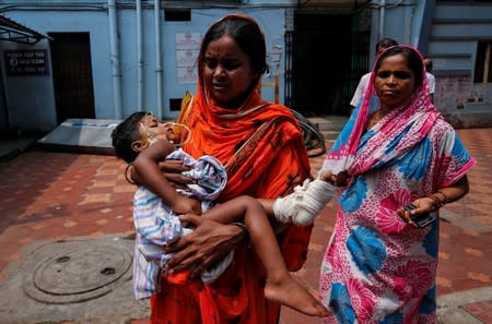 A woman carries her daughter for treatment at a government hospital during a strike by doctors demanding security after the recent assaults on doctors by the patients' relatives, in Kolkata