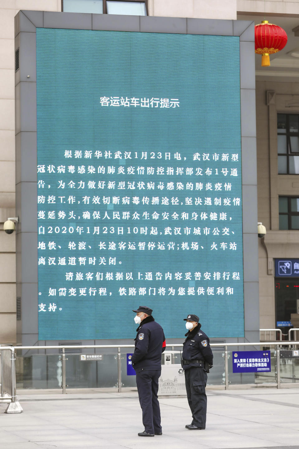 Police stand near a billboard announcing the closure Hankou Railway Station in Wuhan in central China's Hubei Province, Thursday, Jan. 23, 2020. China closed off a city of more than 11 million people Thursday in an unprecedented effort to try to contain a deadly new viral illness that has sickened hundreds and spread to other cities and countries amid the Lunar New Year travel rush. (Chinatopix via AP)