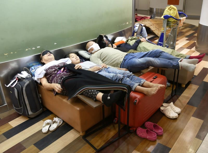 Stranded passengers take rest as train services were suspended due to a heavy rain, at Narita international airport in Narita