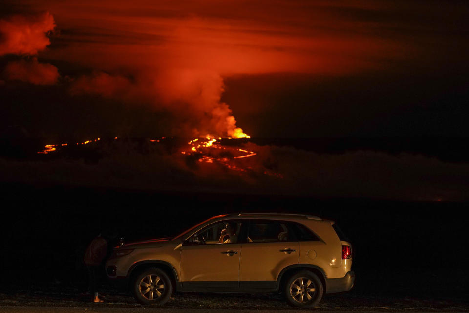 Un hombre conversa por teléfono desde su auto a lo largo de Saddle Road, la principal carretera que une las costas este y oeste de la Isla Grande de Hawai, al tiempo que el volcán Mauna Loa hace erupción el miércoles 30 de noviembre de 2022, cerca de Hilo, Hawai. (AP Foto/Gregory Bull)