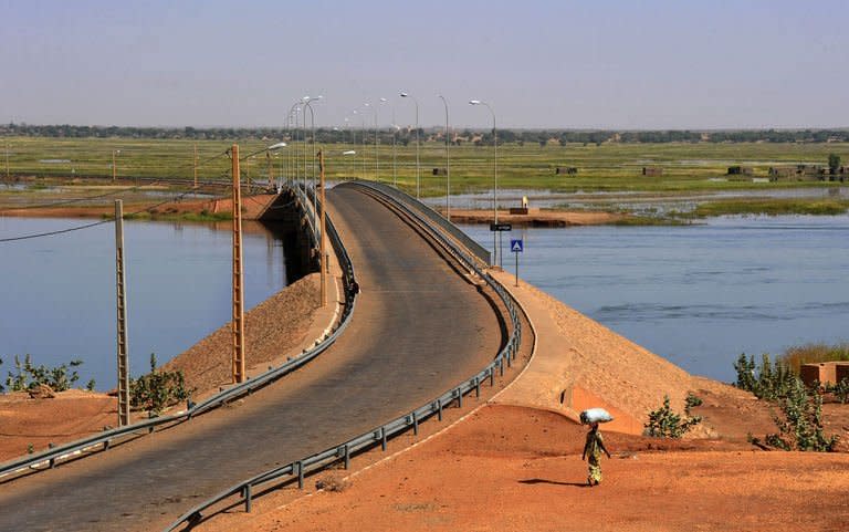 A woman walks by the Gao bridge on the Niger River guarded by French soldiers on February 3, 2013 in Gao