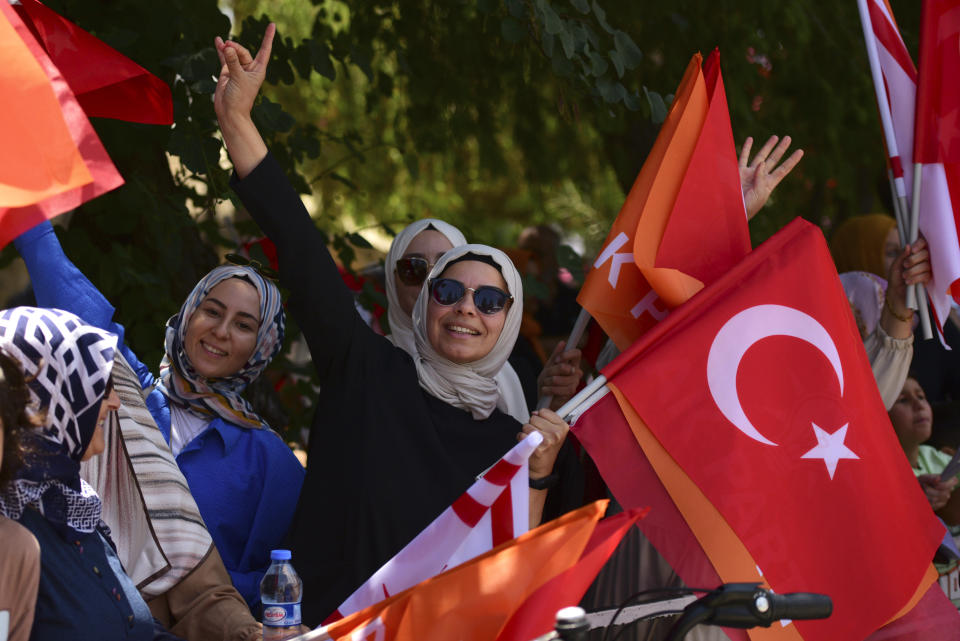 People hold Turkish and Turkish Cypriot breakaway flags as they wait by a street side for the arrival of Turkish President Recep Tayyip Erdogan, in the Turkish occupied area of the divided capital Nicosia, Cyprus, Monday, June 12, 2023. Erdogan is in the Turkish occupied area of north part of the Cyprus island on his first trip after his re-election. (AP Photo/Nedim Enginsoy)