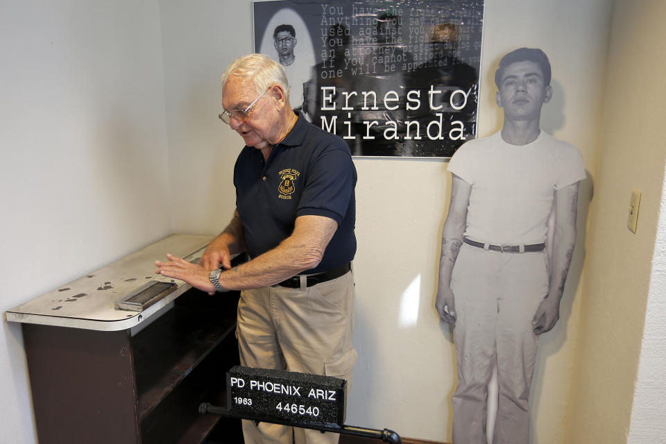 FILE - Retired Phoenix Police Capt. Carroll Cooley demonstrates Wednesday, March 13, 2013, at the Phoenix Police Museum in Phoenix, how Ernesto Miranda was fingerprinted on the same fingerprinting device used on Miranda. Cooley, the arresting officer in the landmark self-incrimination case that led in part to the Supreme Court's Miranda rights ruling requiring officers to read suspects their rights, died on Monday, May 29, after an unspecified illness, the department confirmed Friday, June 2, 2023. He was 87. (AP Photo/Matt York, File)