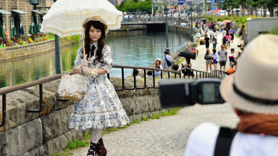 A young woman sporting Lolita fashion poses for photographs along the Otaru Canal in the background on June 29, 2014 in Otaru, Hokkaido, Japan. About 90 girls and young women decked out in lacy Lolita fashions participated in a photo session and tea party event in the port city. - The Asahi Shimbun/Getty Images