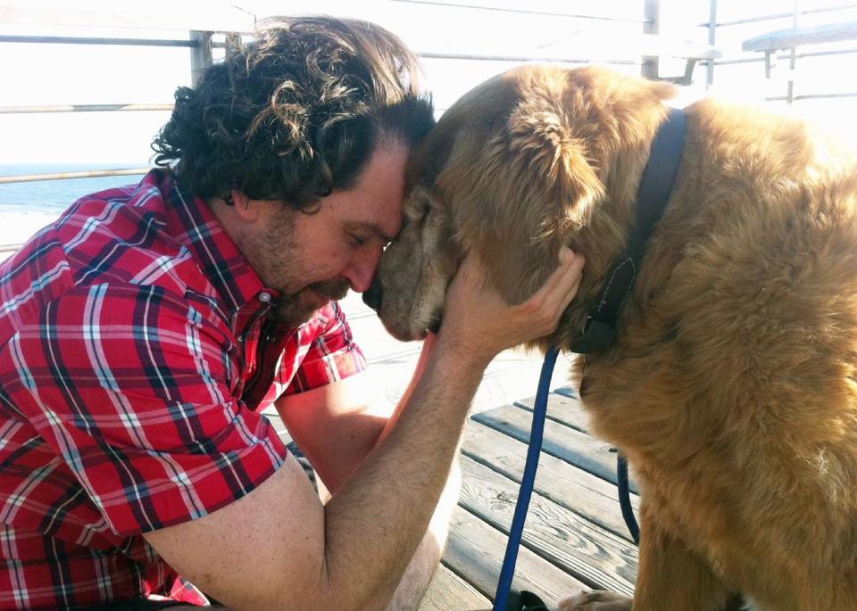 In this 2010 photo provided by Explore.org, philanthropist Charlie Annenberg, left, nuzzles his golden retriever, Lucky, at the Pipeline Beach in Ehukai Beach Park, Haleiwa, Hawaii. For 16 years, Lucky has been his sidekick, soul mate and inspiration, said Annenberg. (AP Photo/Explore.org)