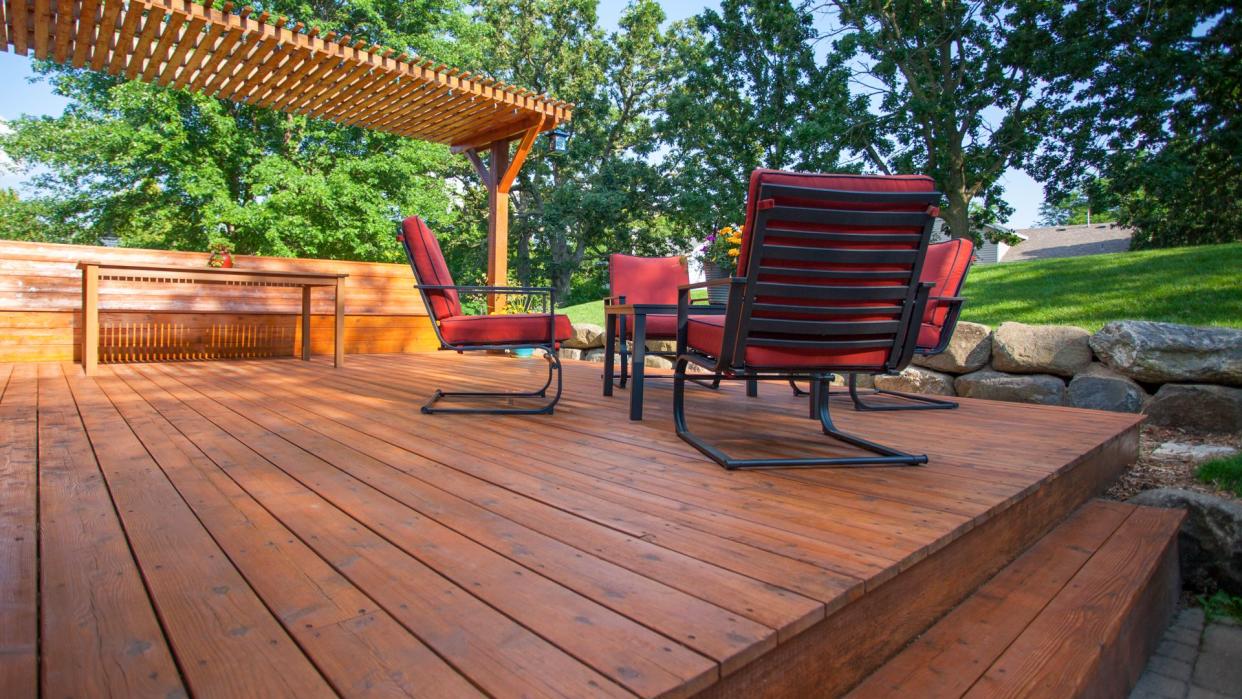 Backyard deck with deck chairs and a pergola on a sunny summer day.