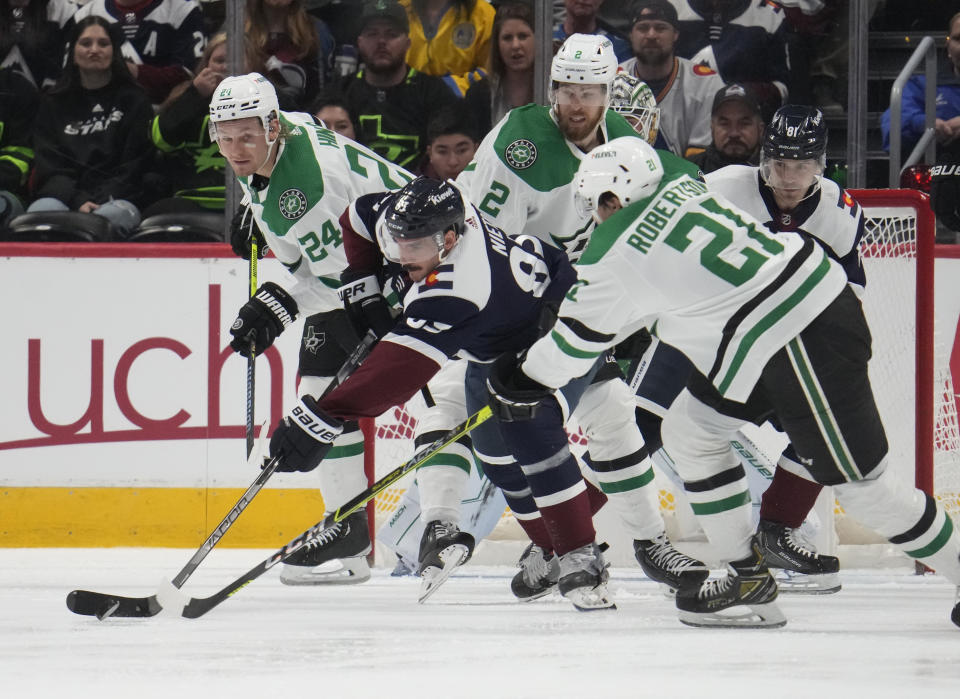 Colorado Avalanche left wing Matt Nieto, front center, fights to collect the puck as, Dallas Stars center Roope Hintz, front left, left wing Jason Robertson, front right, and defenseman Jani Hakanpaa, back, cover in the second period of an NHL hockey game Saturday, April 1, 2023, in Denver. (AP Photo/David Zalubowski)