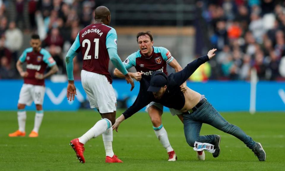 West Ham United’s Mark Noble clashes with a fan who invaded the pitch who has invaded the pitch in their defeat to Burnley.