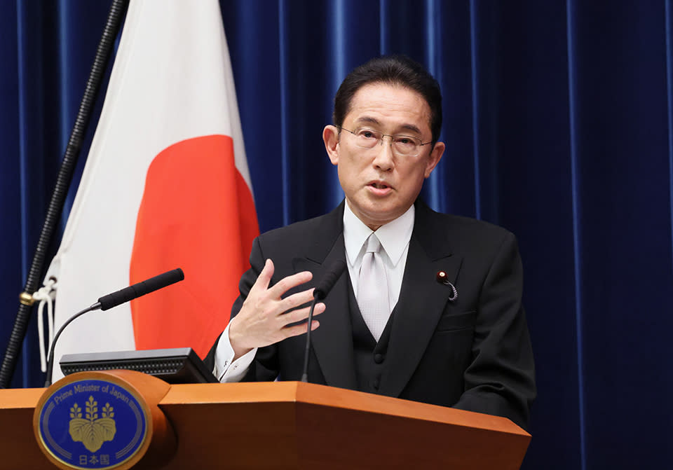 Prime Minister of Japan Fumio Kishida speaks on the podium in front of his country's flag.