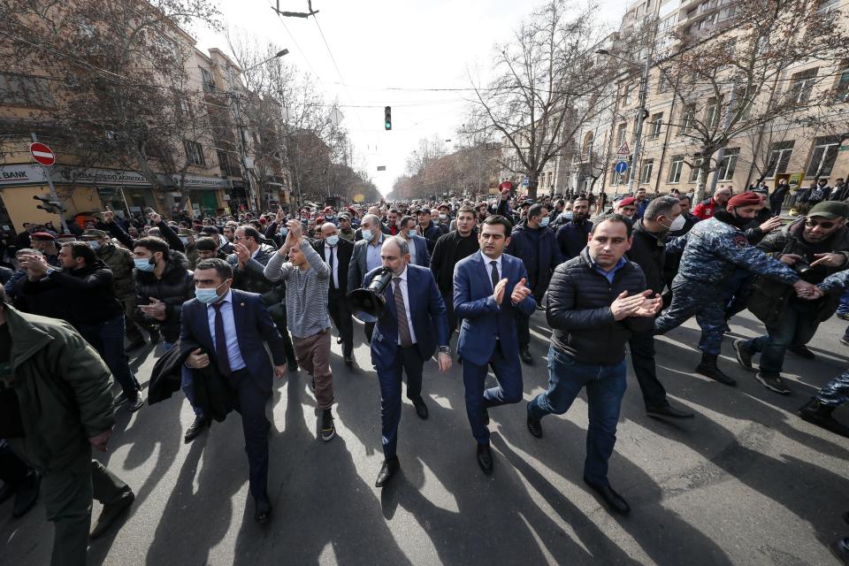 Armenian Prime Minister Nikol Pashinyan, center, surrounded by his supporters, speaks through a loudspeaker during a rally in the central in Yerevan, Armenia, Thursday, Feb. 25, 2021. Armenia's prime minister accused top military officers on Thursday of attempting a coup after they demanded he step down, adding fuel to months long protests calling for his resignation following the nation's defeat in a conflict with Azerbaijan over the Nagorno-Karabakh region. (Tigran Mehrabyan/PAN Photo via AP)