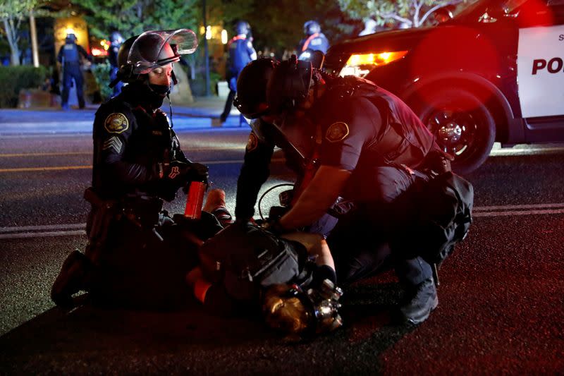 FILE PHOTO: Police officers detain a demonstrator during a protest against police violence and racial injustice in Portland