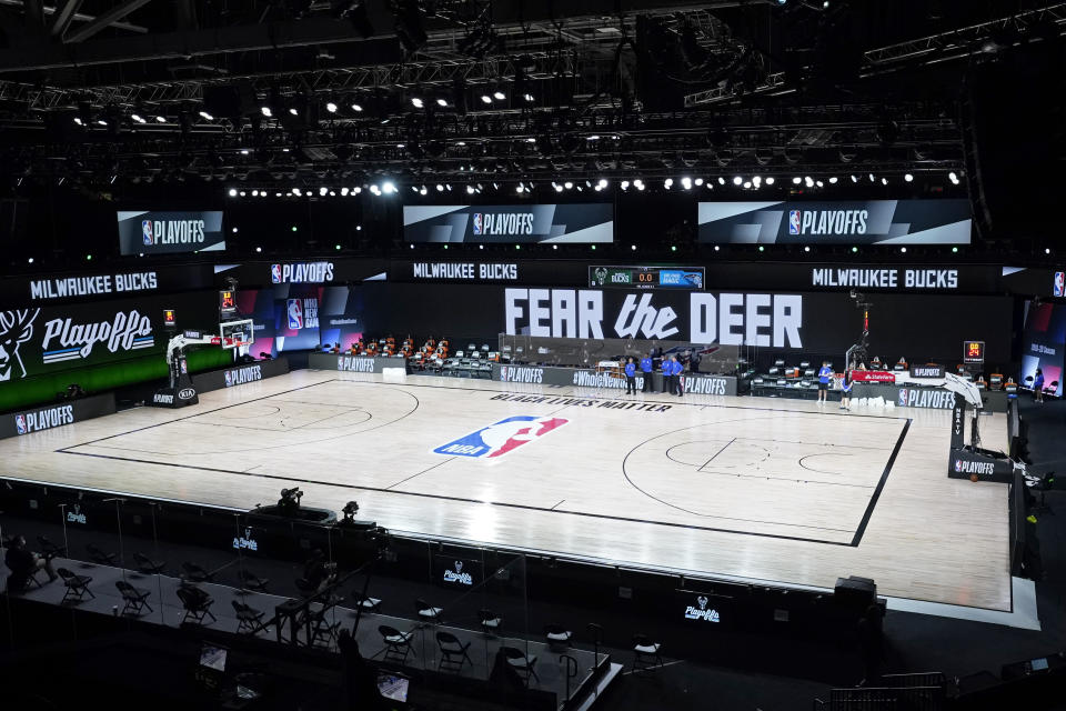 Officials stand beside an empty court at the scheduled start of an NBA basketball first round playoff game between the Milwaukee Bucks and the Orlando Magic, Wednesday, Aug. 26, 2020, in Lake Buena Vista, Fla. The Milwaukee Bucks didn't take the floor in protest against racial injustice and the shooting of Jacob Blake, a Black man, by police in Kenosha, Wisconsin. (AP Photo/Ashley Landis, Pool)