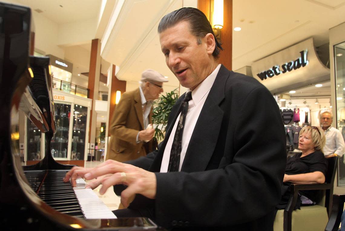 Gino Gaetano plays the piano at the old food court in Aventura Mall on Tuesday evening, Oct. 5, 2010, as a listener dances in the background.