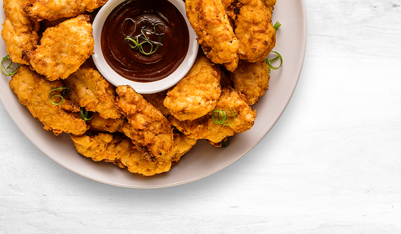 Plate of fried chicken with a dark red-brown sauce in the middle.