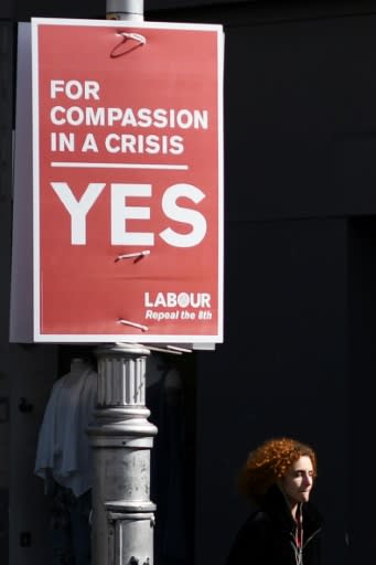 A woman walks past a poster urging a yes vote