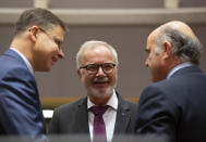 European Commissioner for An Economy that Works for People Valdis Dombrovskis, left, speaks with European Central Bank Vice-President Luis de Guindos, right, and President of the European Investment Bank Werner Hoyer during a meeting of EU finance ministers at the Europa building in Brussels, Tuesday, Feb. 18, 2020. EU finance ministers meet Tuesday to discuss tax havens. (AP Photo/Virginia Mayo)