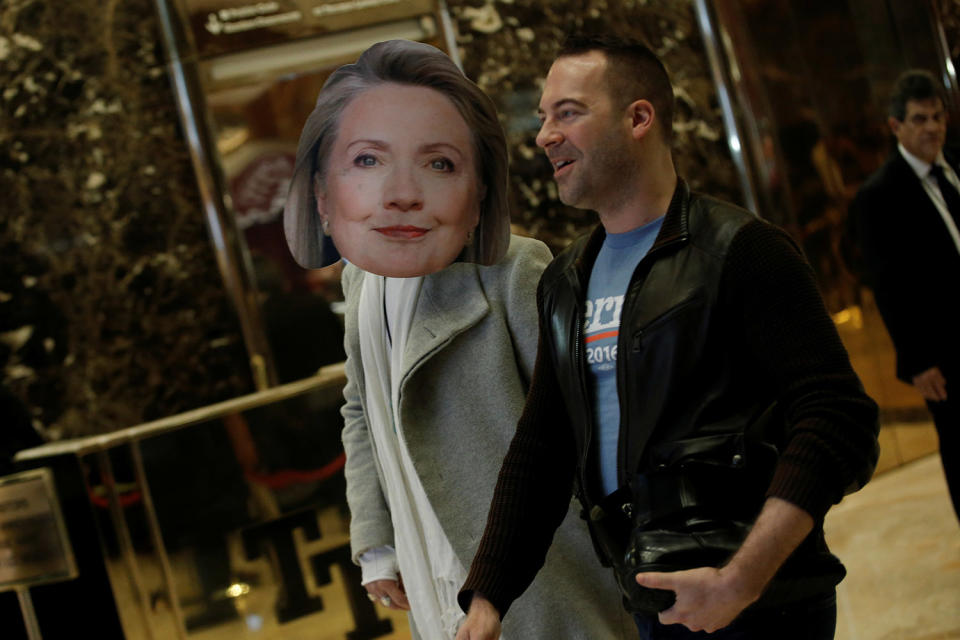 A man wearing a Hillary Clinton mask walks through the lobby of Trump Tower