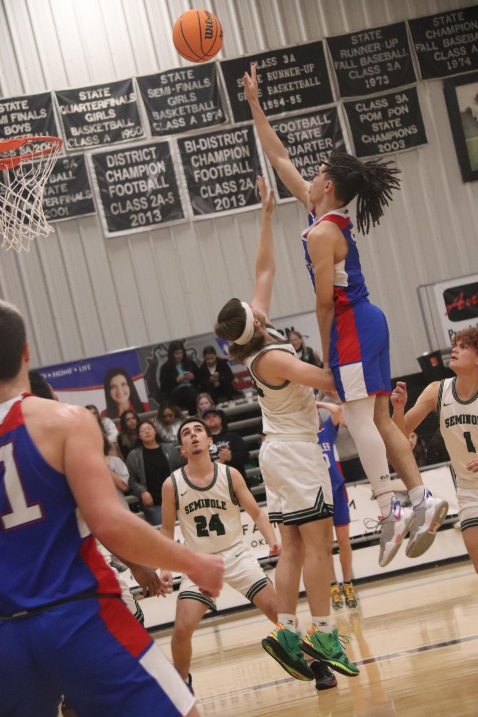 Chandler's Isaiah Holland (right) puts up a shot over Seminole's Jaxon Smith Tuesday night in Meeker.