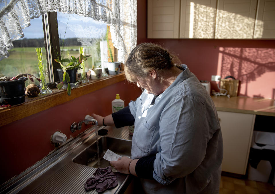 Carmall Casey washes pills from an old pack of tapentadol down the sink while going through her box of medicine in her kitchen in Black River, Tasmania, Australia, Wednesday, July 24, 2019. She thought she had thrown all her opioids away. Casey's tried to quit in the past, returning drugs to pharmacies and dumping them down the sink. But eventually, the pain would grow unbearable, so she'd take the drugs again. (AP Photo/David Goldman)