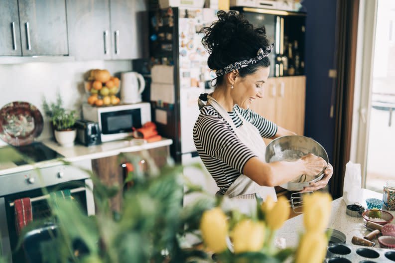 A woman baking muffins in her kitchen.