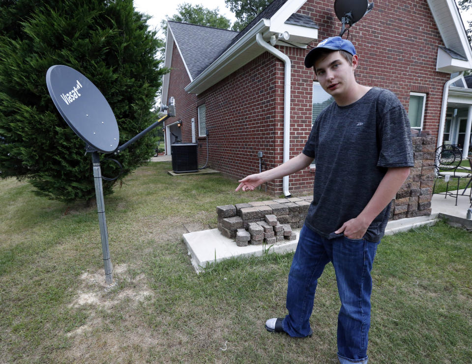 In this May 8, 2019, photo, Riley Shaw talks about his family's internet at his home outside Starkville, Miss. The satellite dish allows a certain amount of high-speed data each month and then slows to a crawl. (AP Photo/Rogelio V. Solis)