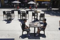 FILE - In this July 18, 2020 file photo, young patrons eat a meal on a closed-off street near sparsely sat tables in Burbank, Calif. California's unemployment rate has fallen to 11.4% in August. The Employment Development Department says the state added 101,900 jobs in August. Most of those were government jobs, including temporary positions for the U.S. Census. California lost more than 2.6 million jobs in March and April because of the coronavirus. (AP Photo/Marcio Jose Sanchez, File)