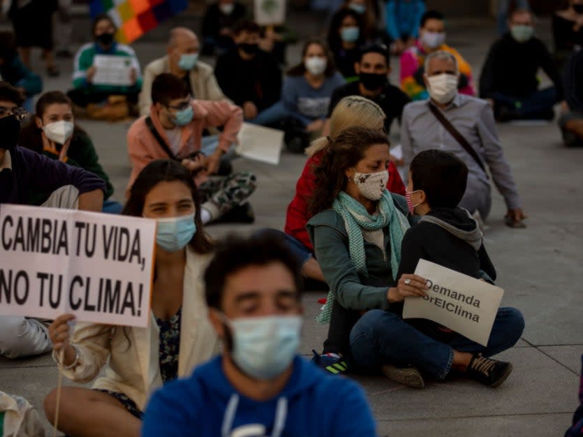 Youth environmental activists wear protective face masks and practice social distancing guidelines as one protester sits with a child and holds a placard reading ‘Climate demand’ during a protest in Madrid in September 2020 (Getty Images)