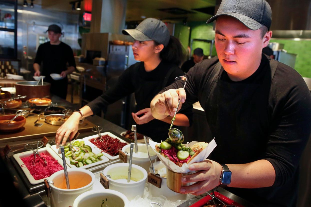 Sue Crenshaw (left) and Caleb Anderson (right) build sandwiches and salads for customers at Brassica in Upper Arlington in 2019.