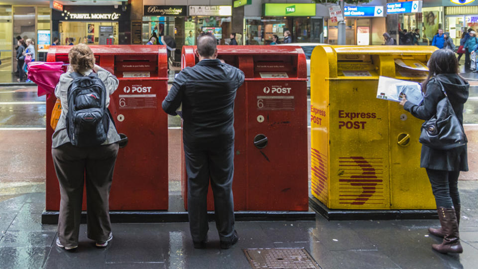 people lined up mailing items in Australia post boxes