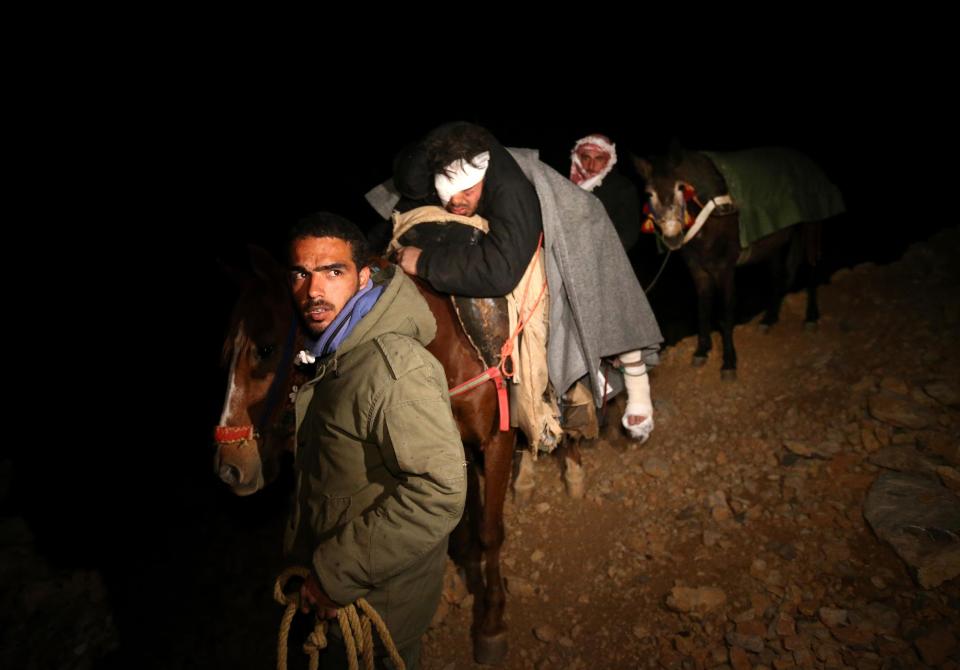 In this picture taken on early Sunday April 20, 2014, Saleh Zawaraa, 28, center, arrives on horseback after being severely injured by a tank shell as he tried to bring bread into the Syrian village of Beit Jinn, near the Israeli-occupied Golan Heights. He and other Syrians refugees came over 2,814-meter (9,232-foot) Mount Hermon (Jabal el-Sheikh), into the town of Chebaa in southeast Lebanon. The village of Beit Jinn has been under siege by Syrian troops for months, and no food and medicine has been allowed to reach thousands of trapped civilians inside.(AP Photo/Hussein Malla)